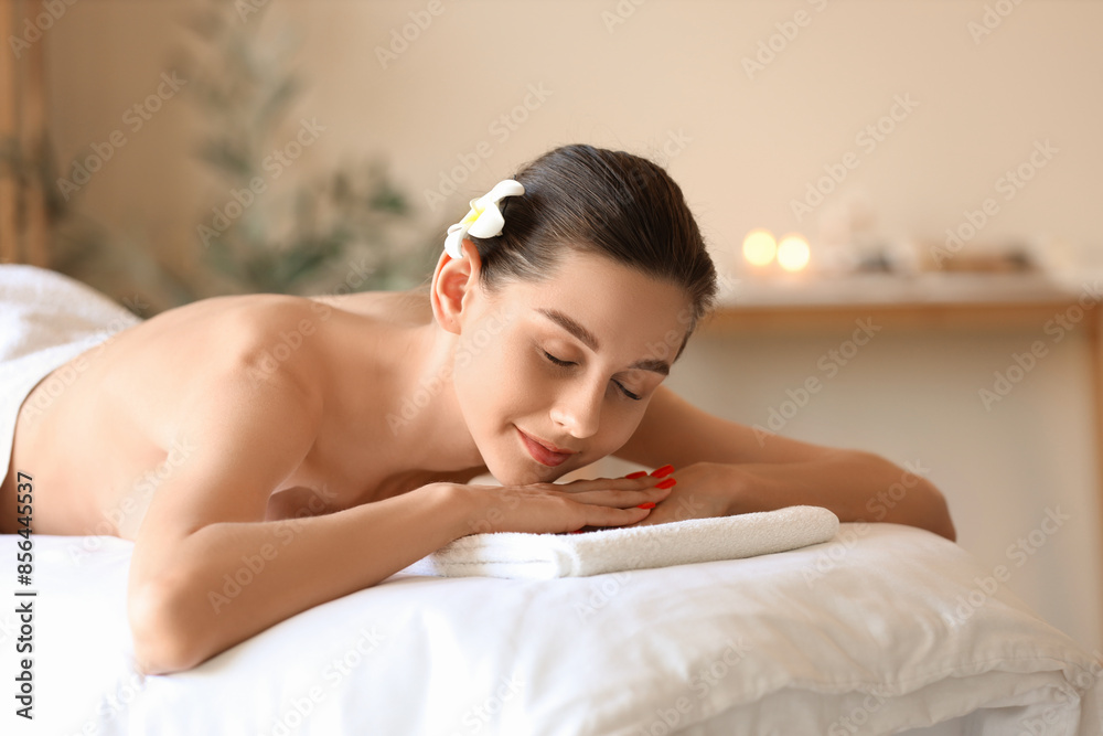 Young woman with flower lying on couch in spa salon