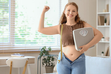 Sticker - Happy young woman in tight jeans with scales at home. Weight gain concept