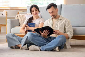 Poster - Religious couple reading Holy Bible on floor at home