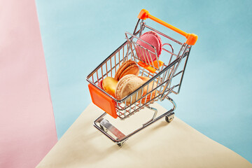 Wall Mural - Multi-colored macarons of different colors and flavors in a supermarket trolley on colored backgrounds