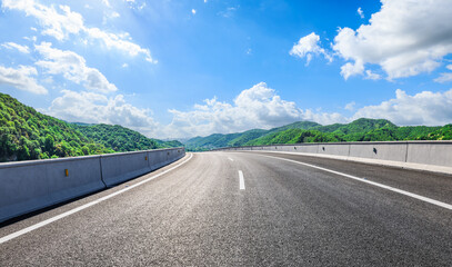 Wall Mural - Asphalt highway road and green mountain with sky clouds natural background on sunny day. Car advertising background.