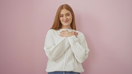 Canvas Print - Smiling young redhead feeling gratitude, standing, hand over chest, in a sweater, isolated on pink. care, health and vibrant lifestyle portrayed.