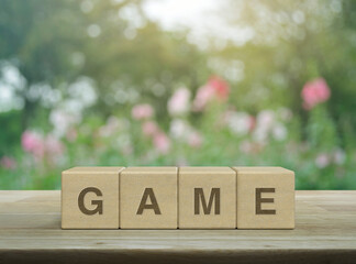 Poster - Game letter on wood block cubes on wooden table over blur pink flower and tree in park, Leisure and education concept