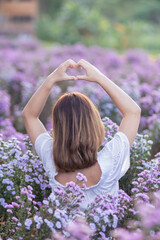 woman raises her hands make heart symbol meaning love and friendship on beautiful morning nature landscape background. Concept ​​using hands to make heart symbol represents meaning of friendship love