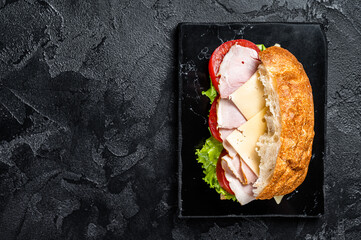 Wall Mural - Hum and cheese sandwich with cheese, tomato and Lettuce. Sub sandwich. Black background. Top view. Copy space