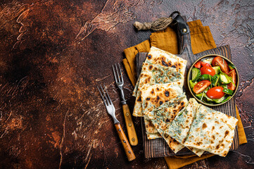 Wall Mural - Freshly baked Turkish Gozleme, flatbread with greens and cheese. Dark background. Top view. Copy space