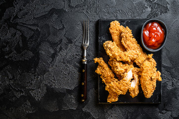 Wall Mural - Breaded chicken strips  Fingers with  Ketchup. Black background. Top view. Copy space