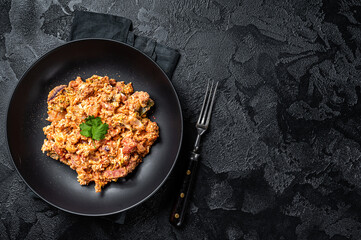 Wall Mural - Turkish  Menemen,  Eggs with tomatoes, green peppers and green onion. Black background. Top view. Copy space