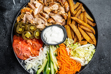 Canvas Print - Shawarma Doner kebab on a plate with french fries and salad. Black background. Top view