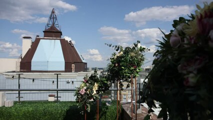 Poster - arch of a wedding ceremony made of flowers against the background of a big city