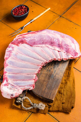 Wall Mural - Raw rack of lamb mutton ribs on butcher board with spices. Orange background. Top view