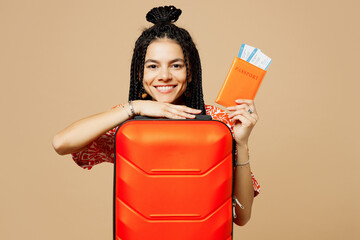 Wall Mural - Traveler woman wears orange casual clothes hold passport ticket bag isolated on plain pastel beige background. Tourist travel abroad in free spare time rest getaway. Air flight trip journey concept.