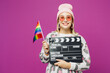 © ViDi Studio - Young happy lesbian woman wear pink animal clothes hold in hand flag classic black film making clapperboard isolated on plain purple background studio portrait Pride day June month love LGBTQ concept