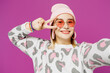 © ViDi Studio - Close up young lesbian woman wear pink animal clothes do selfie shot pov on mobile cell phone cover eye with v-sign isolated on plain purple background studio. Pride day June month love LGBTQ concept.