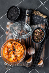 Wall Mural - Homemade kimchi in a glass jar, traditional Korean cuisine. Black background. Top view