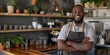© Iryna - A cheerful African bartender in an apron stands confidently, showcasing his professionalism.
