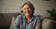 © Hashim - Smiling older woman on cozy couch, enjoying leisure with laughter