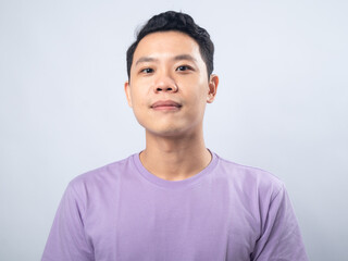 Young Asian man in a lavender t-shirt smiling warmly at the camera. Studio shot on a plain background, highlighting his cheerful expression and casual fashion.