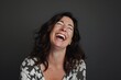 © CogniLens - Portrait of a joyful woman in her 40s laughing over blank studio backdrop
