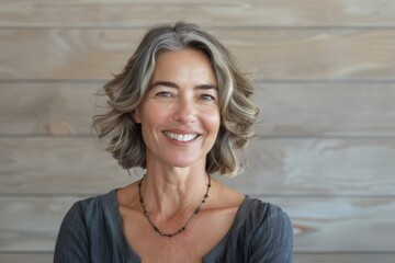 Wall Mural - Portrait of a smiling caucasian woman in her 50s smiling at the camera while standing against light wood minimalistic setup