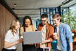 © LIGHTFIELD STUDIOS - Multicultural colleagues in casual attire gathered around a laptop in a hotel lobby during a corporate trip.