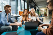 © LIGHTFIELD STUDIOS - Multicultural business colleagues in casual attire work on laptop and collaborate around a table in a cozy setting.