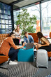 © LIGHTFIELD STUDIOS - Multicultural colleagues in casual attire gathered around a laptop in a hotel lobby during a corporate trip.