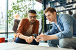 © LIGHTFIELD STUDIOS - male colleagues sit at a hotel table, engrossed in a cell phone together during a corporate trip.