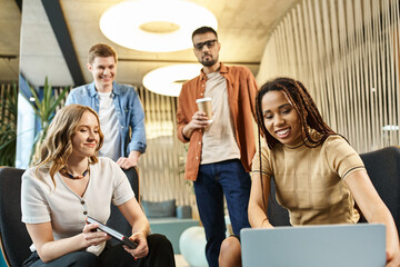 Wall Mural - A diverse group of colleagues in a coworking space, engaged in a discussion while standing around a laptop.