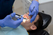 © Ольга Апанасенко - The dentist gives an anesthetic injection into the gum to a boy who is sitting in a dental chair. Dental treatment.