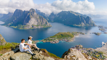 Wall Mural - two people sit on a mountaintop in norway, admiring the stunning view of the fjords and islands. a c