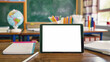 © Jane - iPad with white screen mockup lying on a classroom desk, surrounded by notebooks, pencils, and a globe