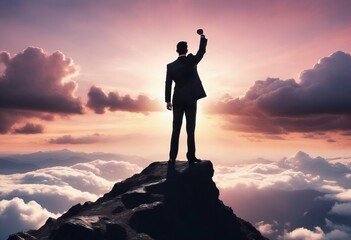 silhouette of a business man in a suit standing on a high mountain peak with one hand raised in a fist, over clouds, little pinky and glossy sunset view, back view	
