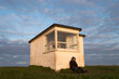 © Nicholas - Sit down and rest a while: A man rests against  coastguard hut at sunrise