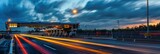A scenic view of a highway toll plaza at dusk with bright light trails from passing cars creating a dynamic composition. The right side of the image offers copy space