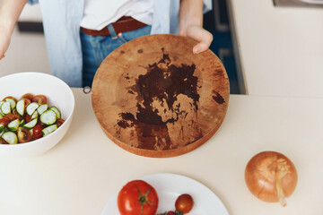 Wall Mural - Woman preparing fresh salad with tomatoes and cucumbers, holding wooden cutting board over bowl