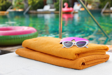 Wall Mural - Beach towels and sunglasses on sun lounger near outdoor swimming pool. Luxury resort