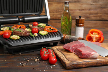 Wall Mural - Electric grill with meat, spices, knife and vegetables on wooden table