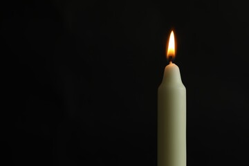 Wall Mural - One burning church candle on black background, space for text