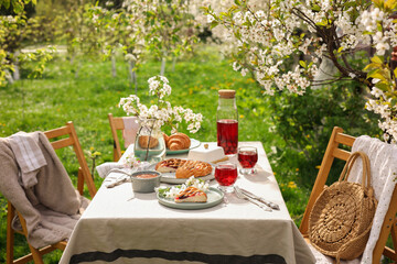 Canvas Print - Stylish table setting with beautiful spring flowers, fruit drink and pie in garden