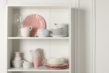 Wall Mural - Different ceramic dishware and glasses on shelves in cabinet indoors