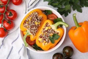 Wall Mural - Quinoa stuffed bell pepper, tomatoes and parsley in bowl on light table, flat lay
