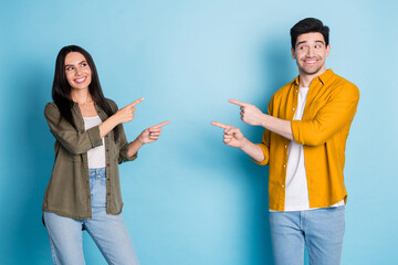 Poster - Portrait of two young people indicate fingers empty space wear shirt isolated on blue color background
