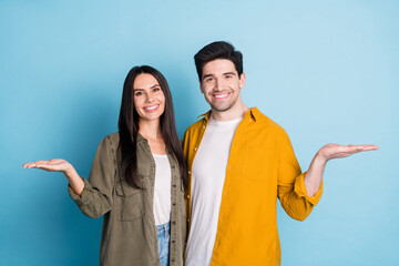 Wall Mural - Photo of two nice young partners hold empty space vs wear shirt isolated on blue color background