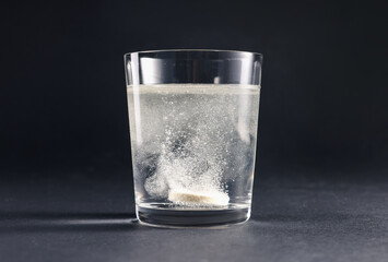 Wall Mural - Effervescent pill dissolving in glass of water on grey table