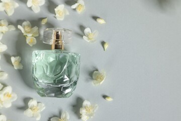 Wall Mural - Aromatic perfume in bottle and beautiful jasmine flowers on grey background, flat lay. Space for text