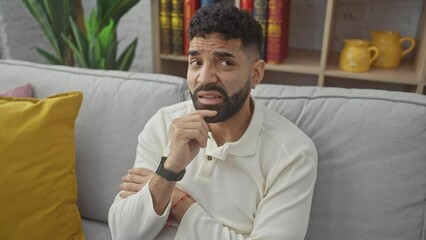 Sticker - Young hispanic man at home, deep in thought with hand on chin, worried, nervous, and concerned about a seeming question