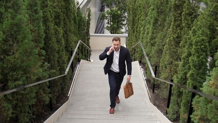 Wall Mural - Caucasian businessman walking up stair and calling manager by using smart phone. Top view of manager talking marketing team and planning financial strategy by telephone while going up stair. Urbane.