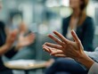 © Business Pics - Hands of a professional making a point in a team meeting, with blurred colleagues in the background, highlighting teamwork and communication.