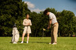 © LIGHTFIELD STUDIOS - A young couple in elegant attire enjoys a game of golf on a lush green field at a prestigious club, embodying the epitome of upper-class leisure.